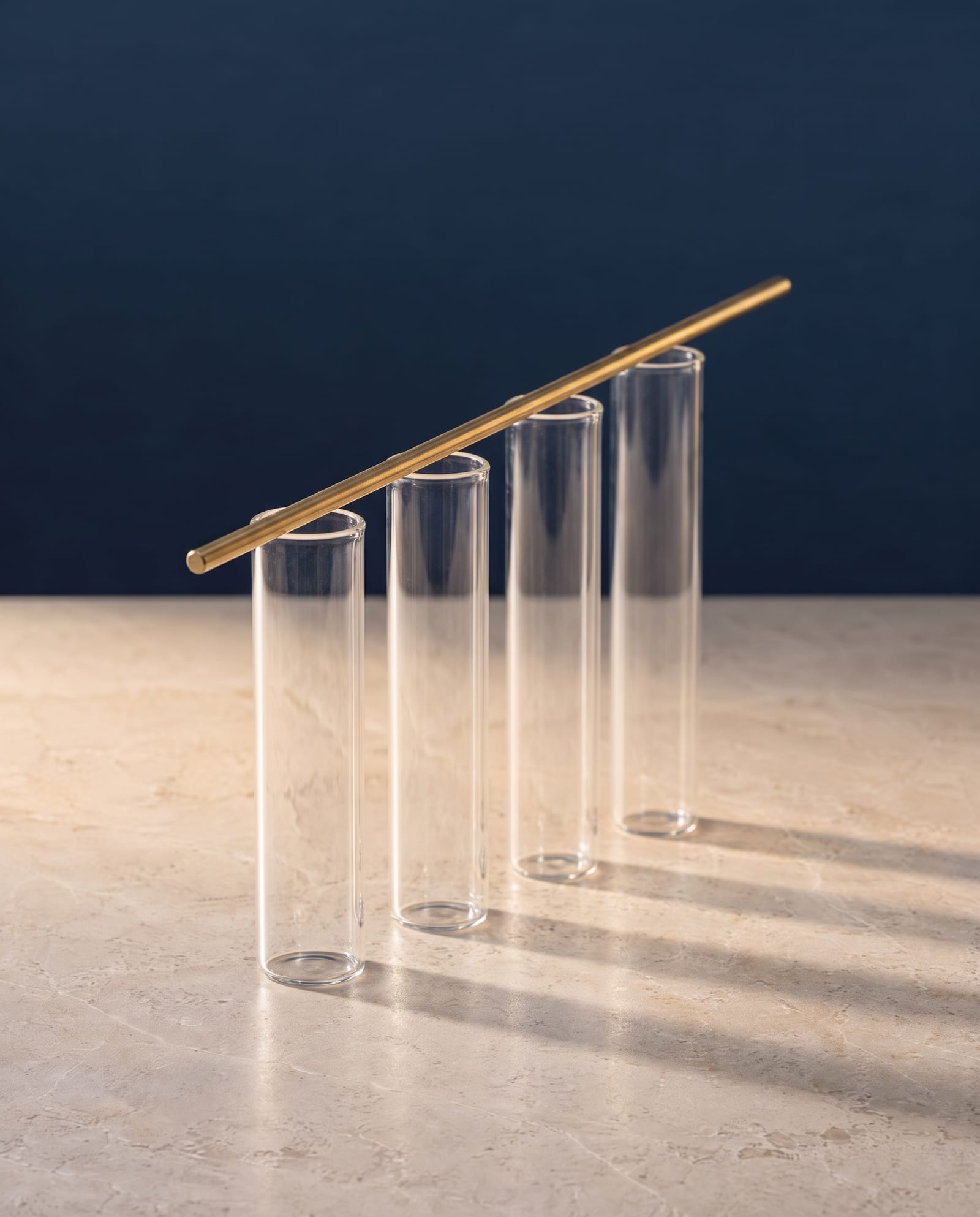 Four identical sample tubes in a row with a thin brass rod rising across them like a trend line.